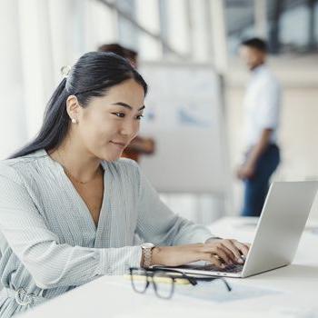 一位职业女性在工作时用笔记本电脑登录她的Patelco Online账户.